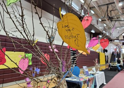 Yellow paper leaf which says "love your mother" on brown paper tree